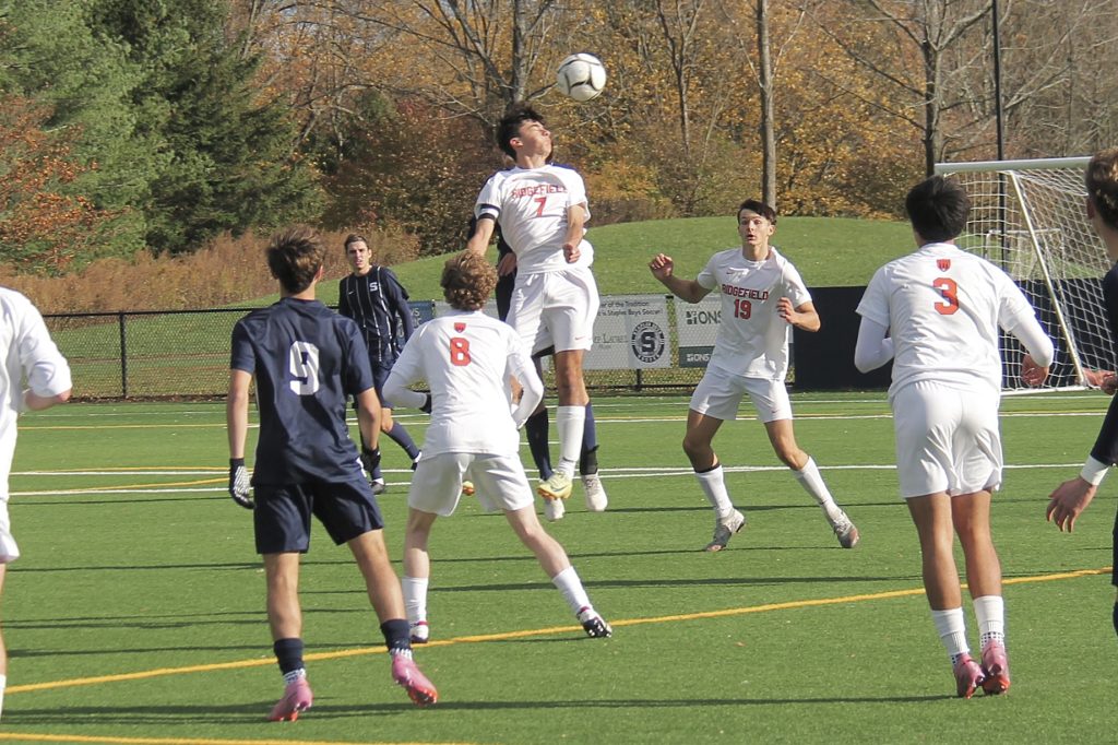 Ridgefield 's Martim Dias Pinto (7) goes up for the ball against Staples. - Photo courtesy of Helen Epley